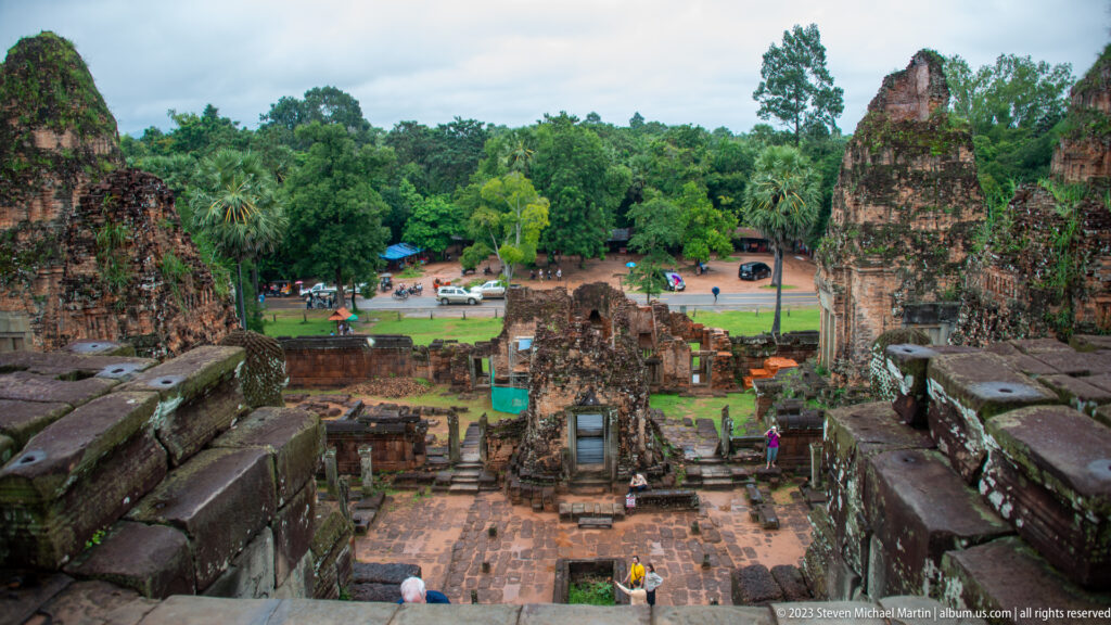Elevated view down Pre Rup’s terraces toward lower brick towers, courtyards, visitors, and surrounding trees.