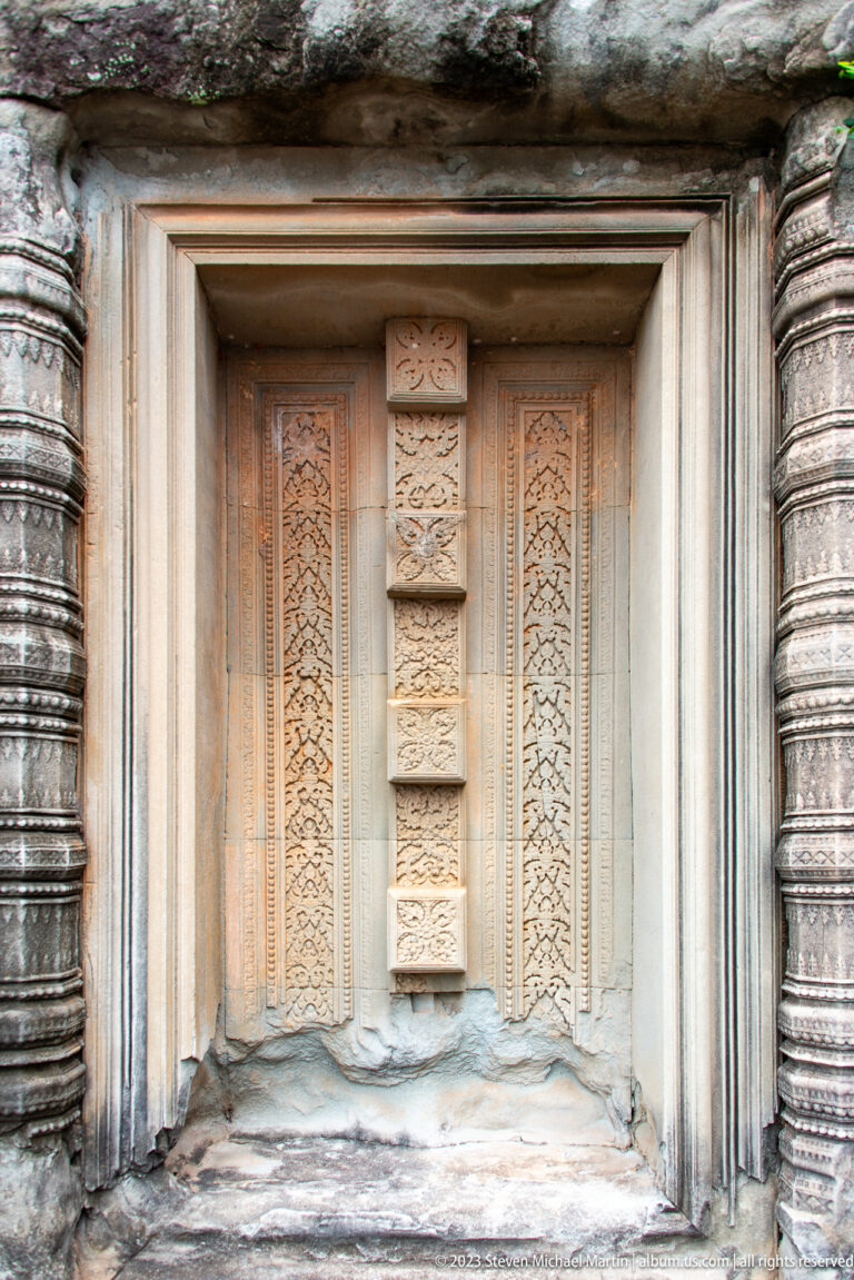 Carved pale sandstone false door with patterned vertical panels and fluted side frames.