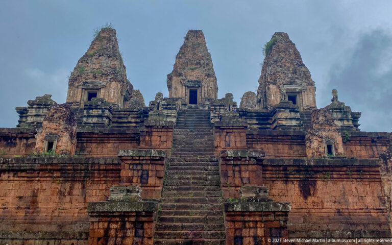 Three brick towers above Pre Rup’s central stair under dark storm clouds.
