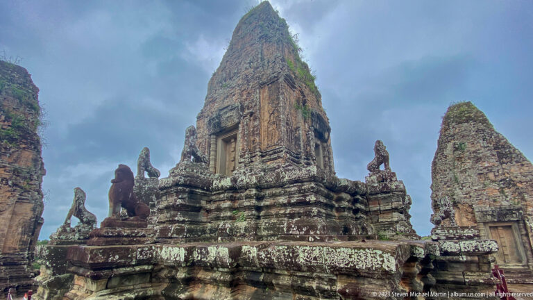 Oblique low-angle view of a central brick tower with lion guardians and smaller towers around the terrace.