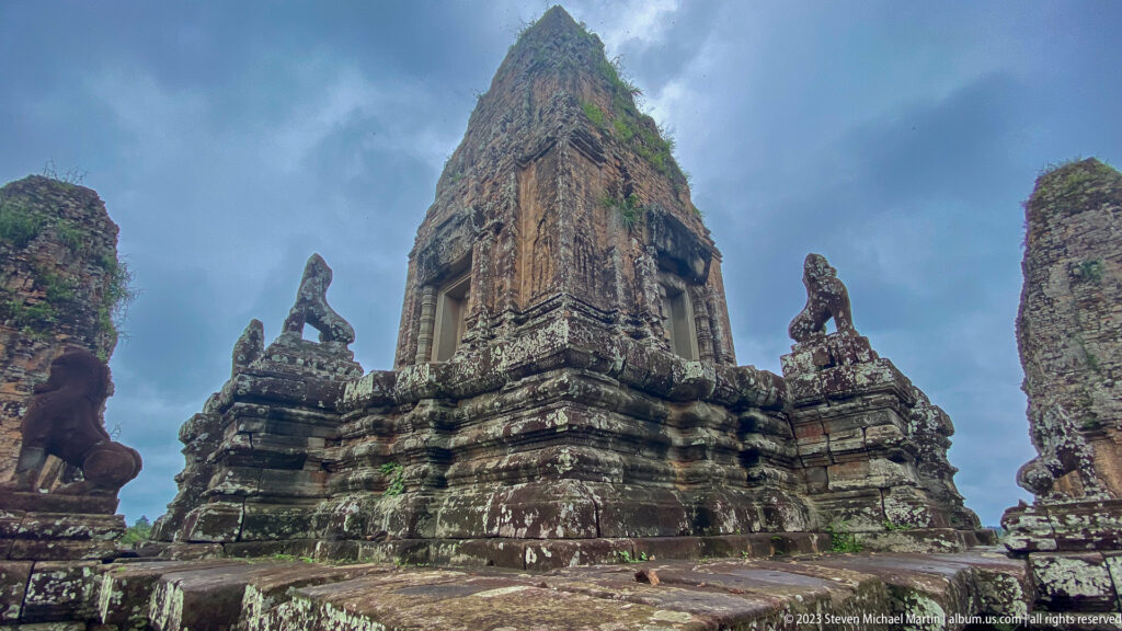 Wide low-angle view of a brick sanctuary tower with lion guardians beneath dark storm clouds.