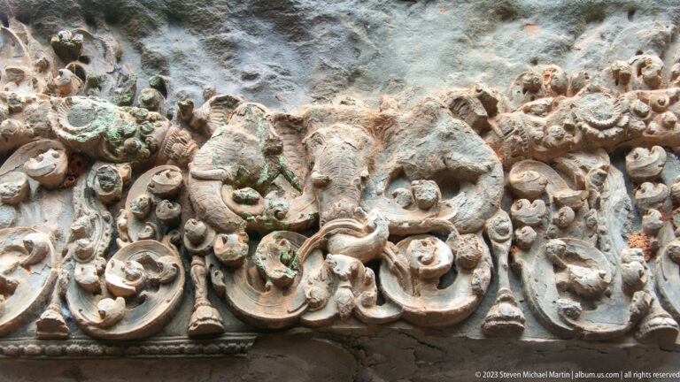 Weathered sandstone lintel carved with scrolling foliage and a central relief motif.
