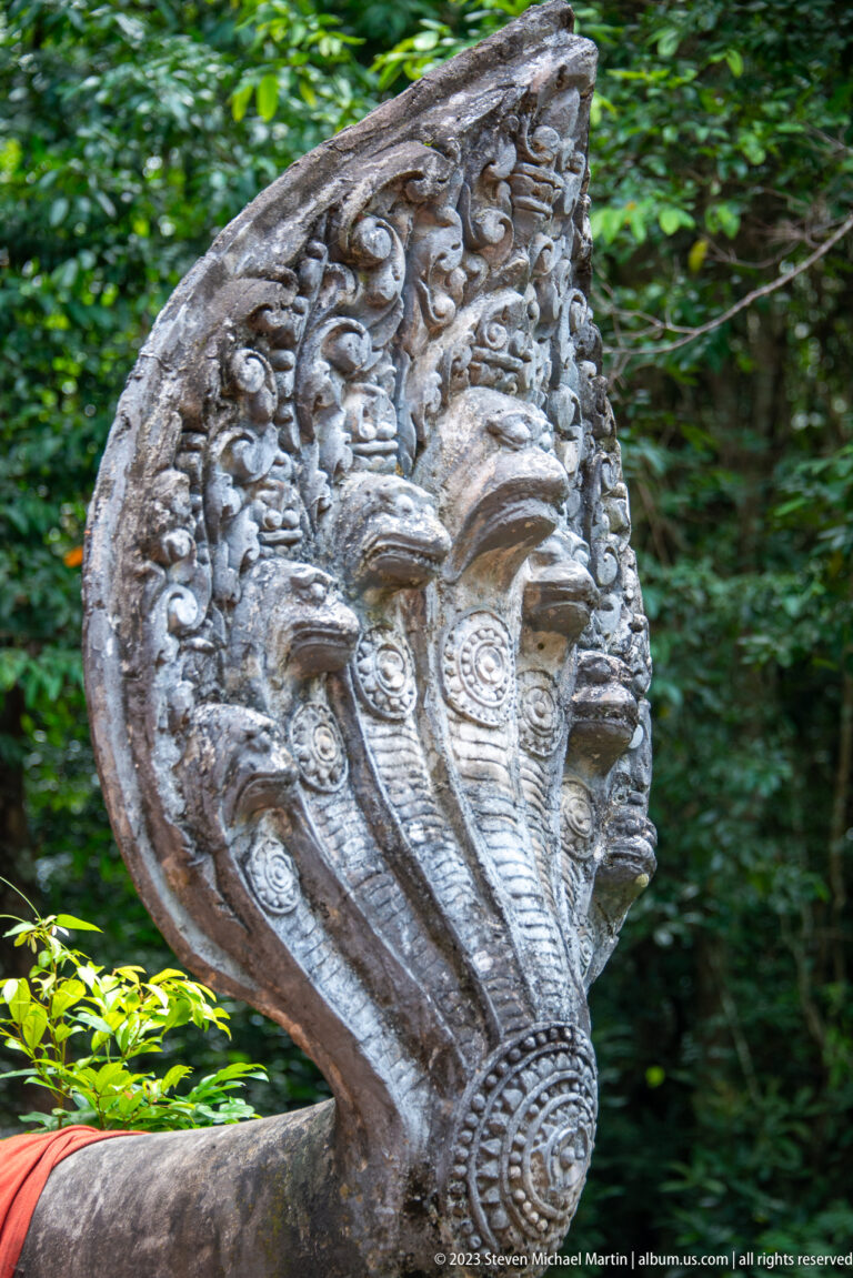 Oblique close view of a five-headed naga terminal with scrolling ornament.