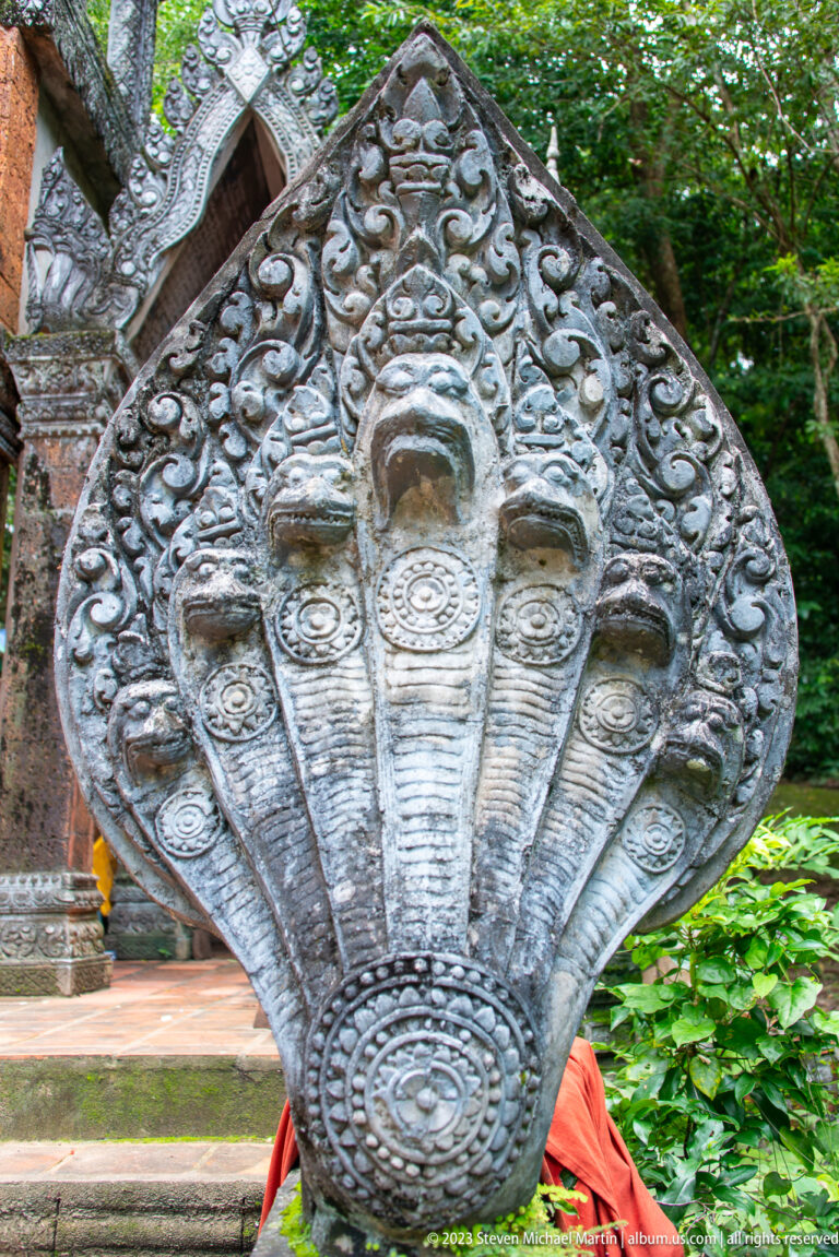 Frontal close-up of five naga heads beneath a pointed carved hood.