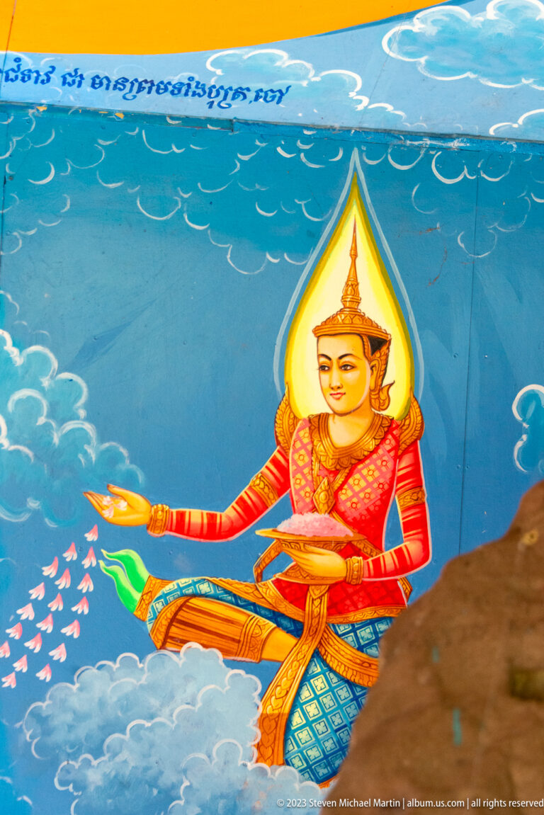 Kneeling celestial woman in red costume extending her hands against a blue cloud background.