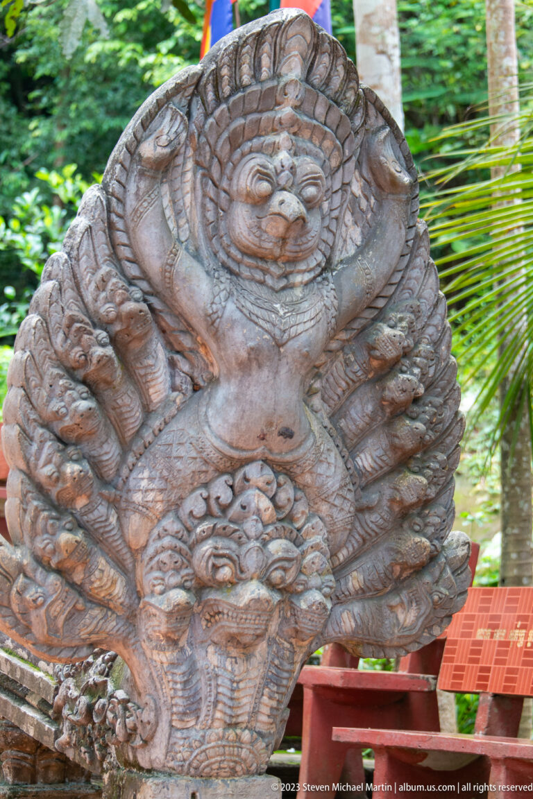 Close view of a multi-headed naga carving with a central guardian face and scrollwork.