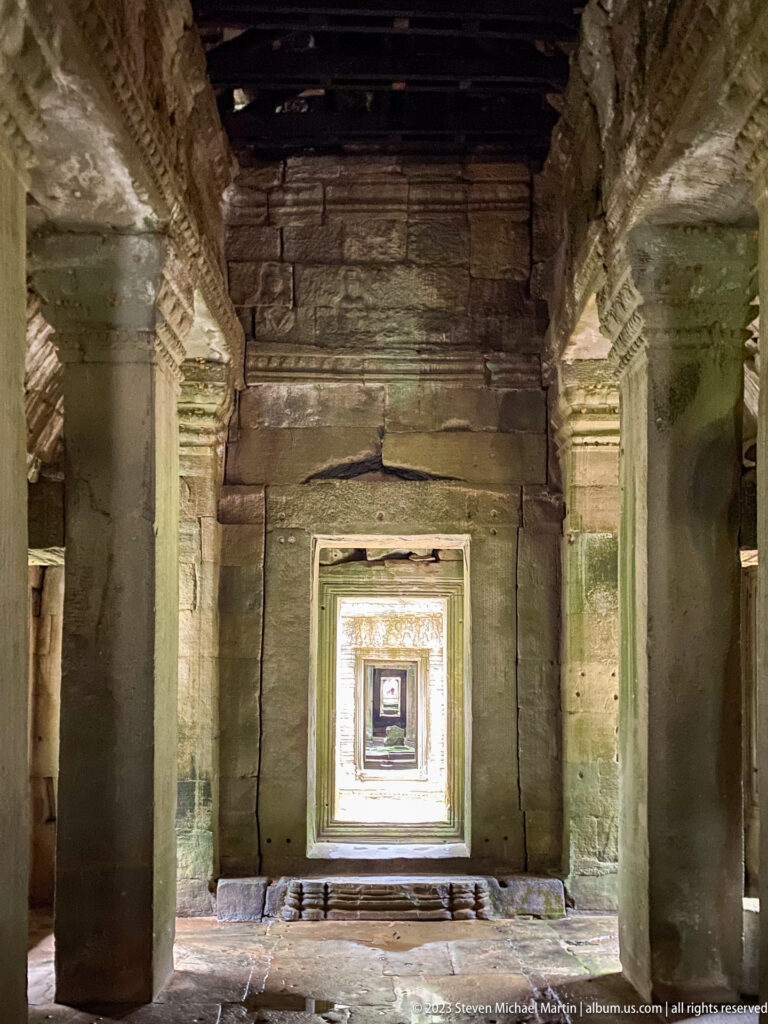 Centered square doorway in a dark sandstone chamber with smaller bright doorways receding beyond.