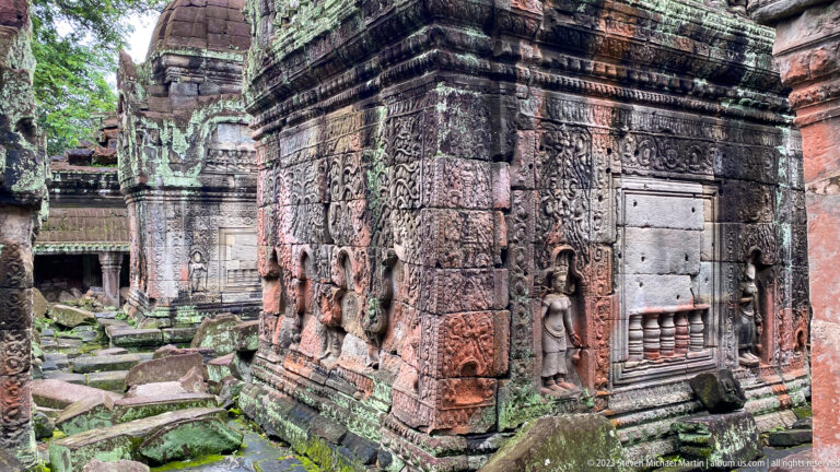Ornate sandstone temple corner with female figures, a blind window, and dense carved ornament.