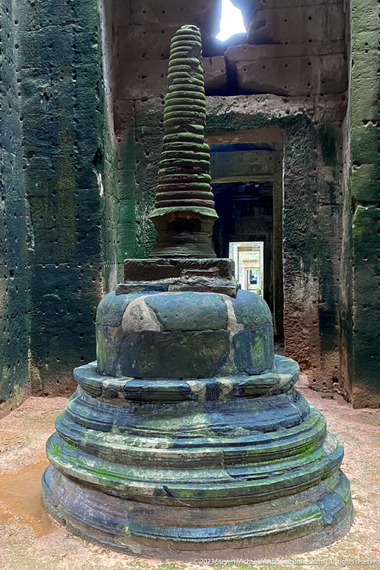 Close view of a tiered stone stupa with broad circular base and ribbed tapering spire.