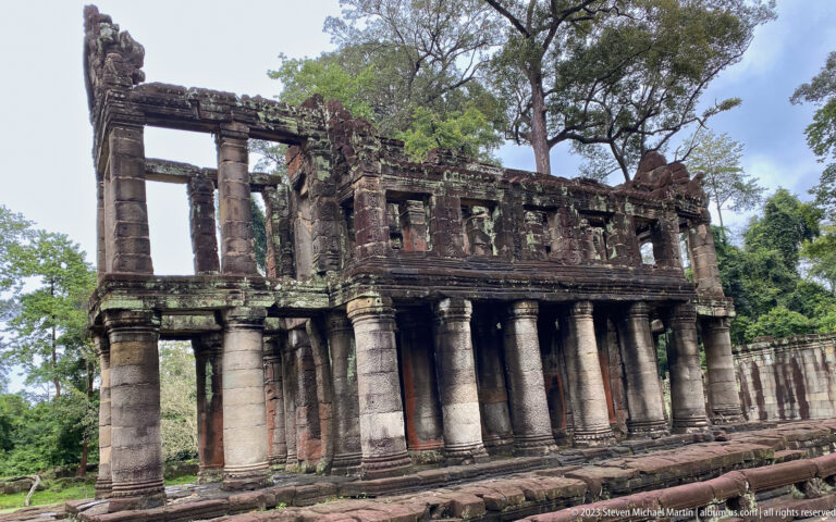 Two-story sandstone building with tall lower columns and a row of open upper bays.