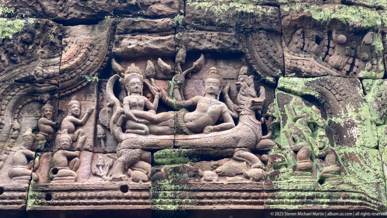 Sandstone relief of two crowned seated figures above a naga with attendants and animals.