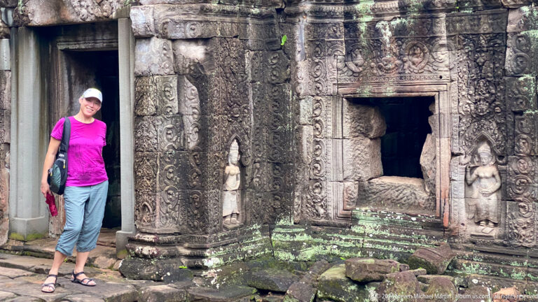 Female visitor beside a carved sandstone shrine opening flanked by standing female figures.