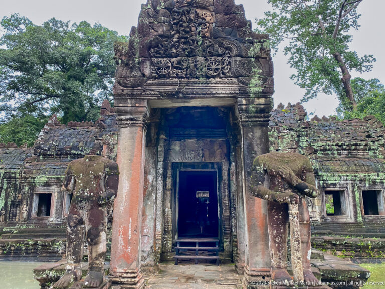 Large carved sandstone gateway flanked by elephant guardians with a dark passage at center.