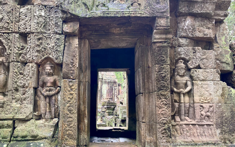 Sandstone doorway flanked by two standing female figures with carved borders and collapsed masonry.