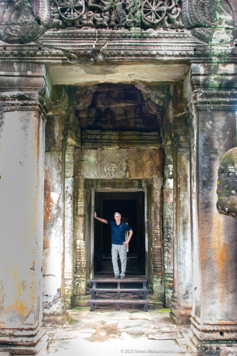 Visitor standing in a dark temple doorway framed by aligned stone lintels and columns.