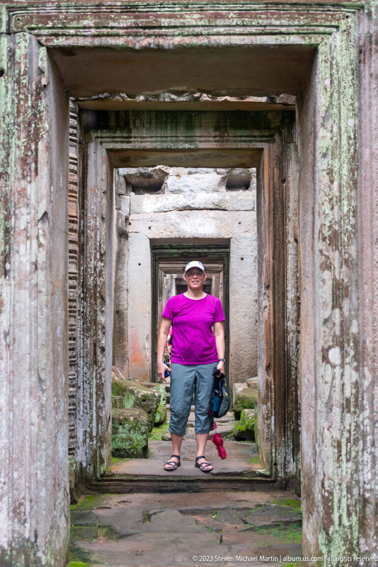 Visitor standing in a corridor of aligned rectangular stone doorways receding into the distance.