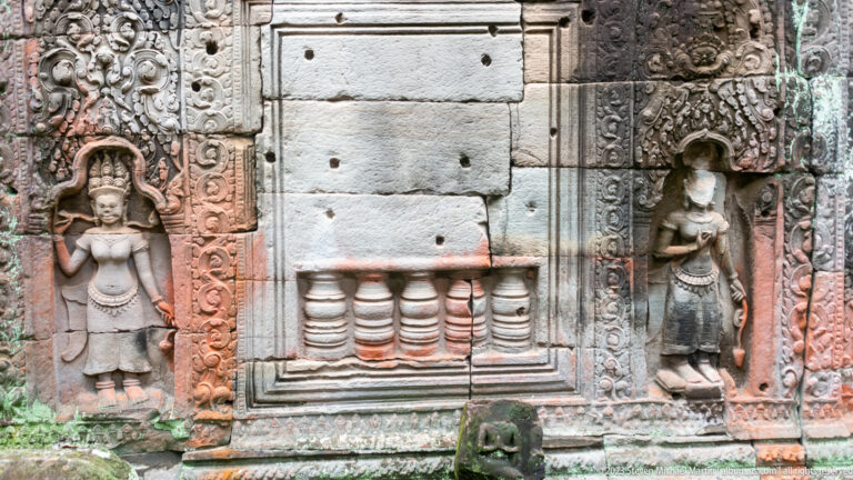Stone wall panel flanked by two standing female reliefs in ornate carved niches.