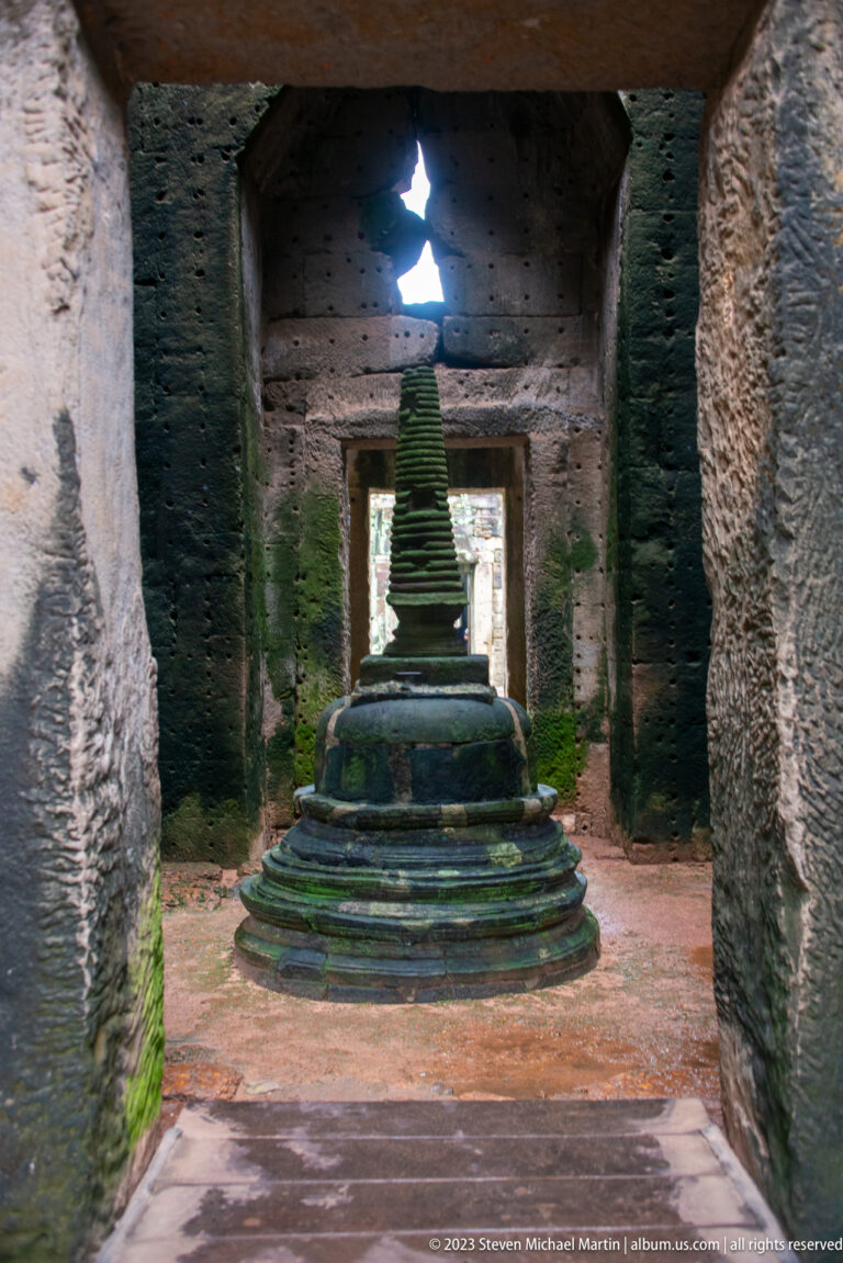 Small tiered stupa on a circular base centered inside a dark stone chamber.