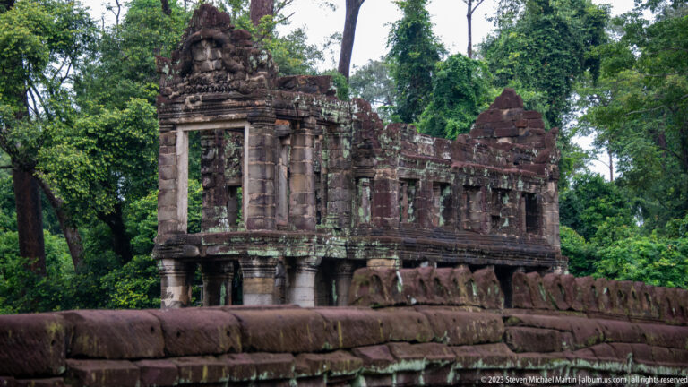 Elevated two-story sandstone temple building with lower columns and an upper row of windows.