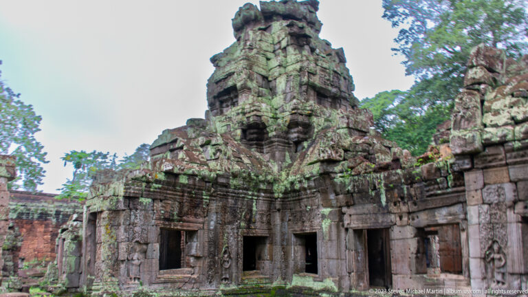 Central sandstone temple tower above a courtyard façade with doorways, windows, and carved panels.