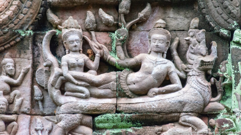 Sandstone relief of two crowned seated figures above a coiling naga with smaller attendants.