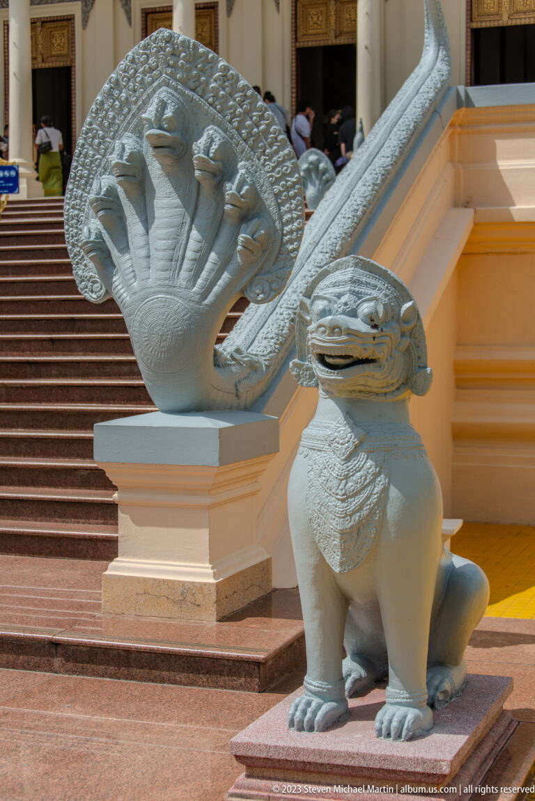 Multi-headed naga balustrade beside palace steps, with a seated lion-like guardian below.
