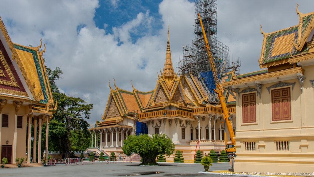 Palace courtyard with gilded gables, cream buildings, clipped shrubs, and the scaffolded Throne Hall spire beyond.