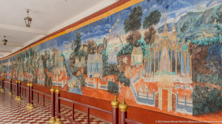 Long Reamker mural of palaces, trees, and figures along a gallery with a red-and-white checkered floor.