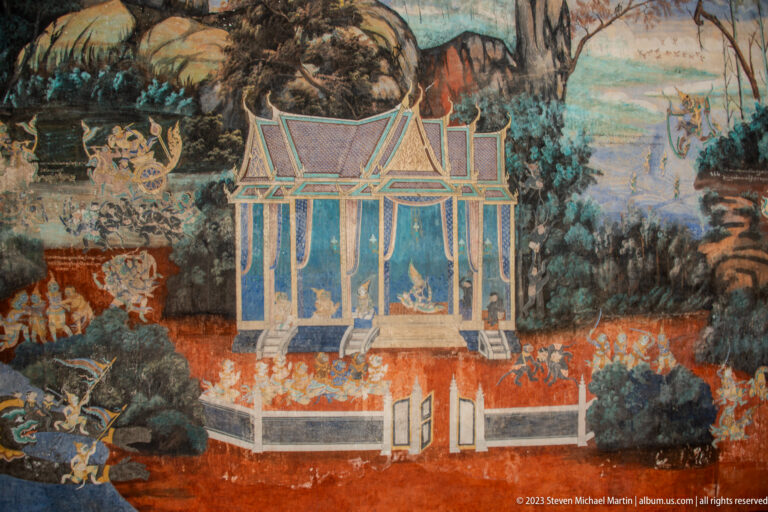 Reamker mural with a blue pavilion, river, trees, walls, and small figures in a painted landscape.