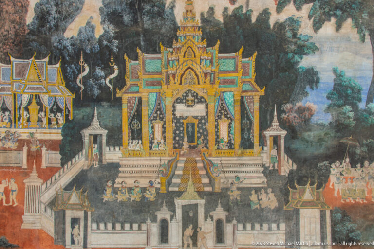 Reamker mural of an ornate shrine with central steps, gilded gables, walls, attendants, and trees.