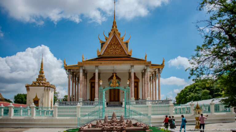 Frontal Silver Pagoda with white columns, turquoise stair and fence, ornate roof, visitors, and a model in front.