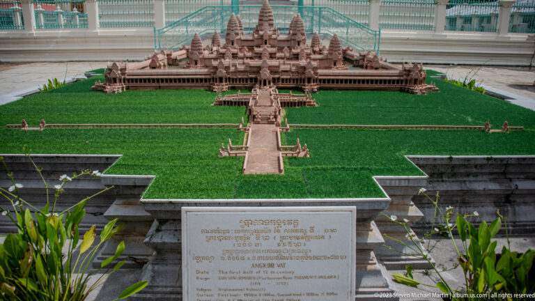 Scale model of Angkor Wat on a green platform with causeway, towers, galleries, and an identification plaque.