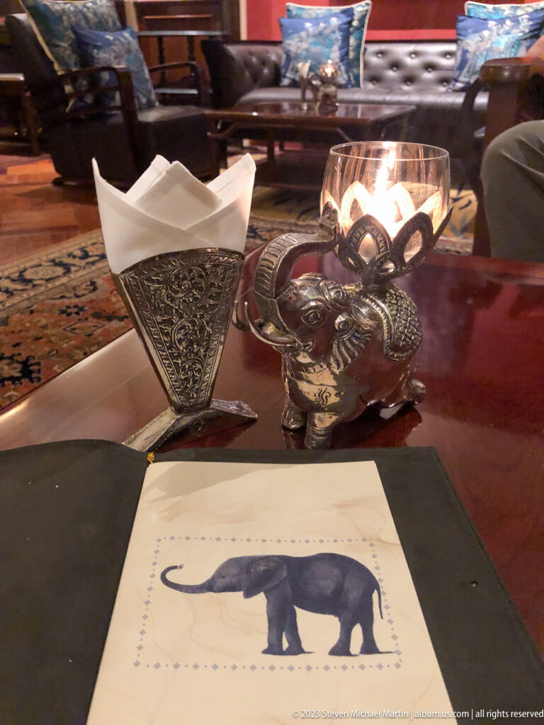 Tabletop with elephant-illustrated stationery, ornate tissue holder, and elephant-shaped candle stand.