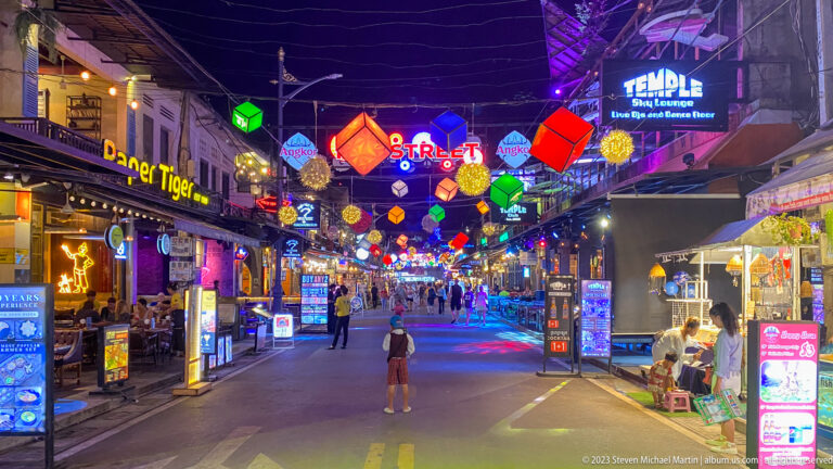 Nighttime view of Siem Reap's Pub Street filled with illuminated lanterns, restaurant signs, pedestrians, and colorful nightlife.