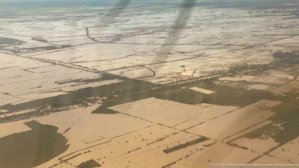 Aerial view of flooded agricultural fields divided by narrow roads and embankments.