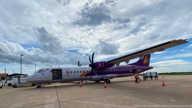 Purple-and-white twin-engine turboprop passenger aircraft parked on an airport apron.