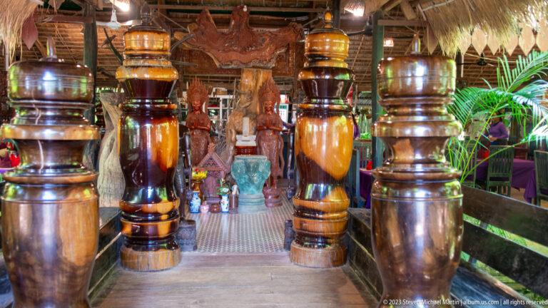Restaurant aisle lined with large polished turned-wood columns and carved decorative figures.