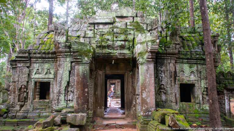 Aligned stone doorways receding through a moss-covered temple structure at Ta Som.