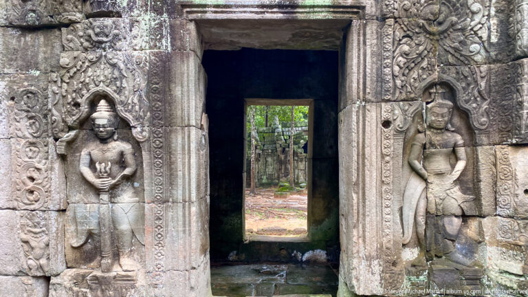 Carved doorway flanked by female deities, with a second opening aligned through the dark interior.