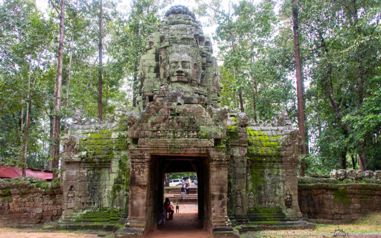 Frontal view of Ta Som face-tower gateway with an open passage through the enclosure wall.
