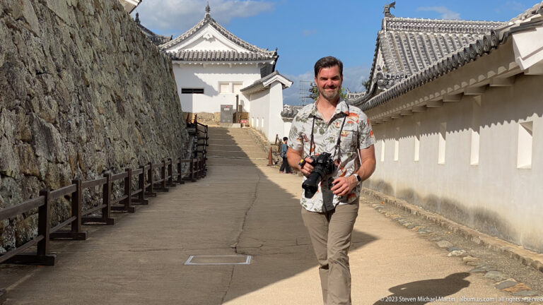 Visitor walking between stone ramparts and white walls