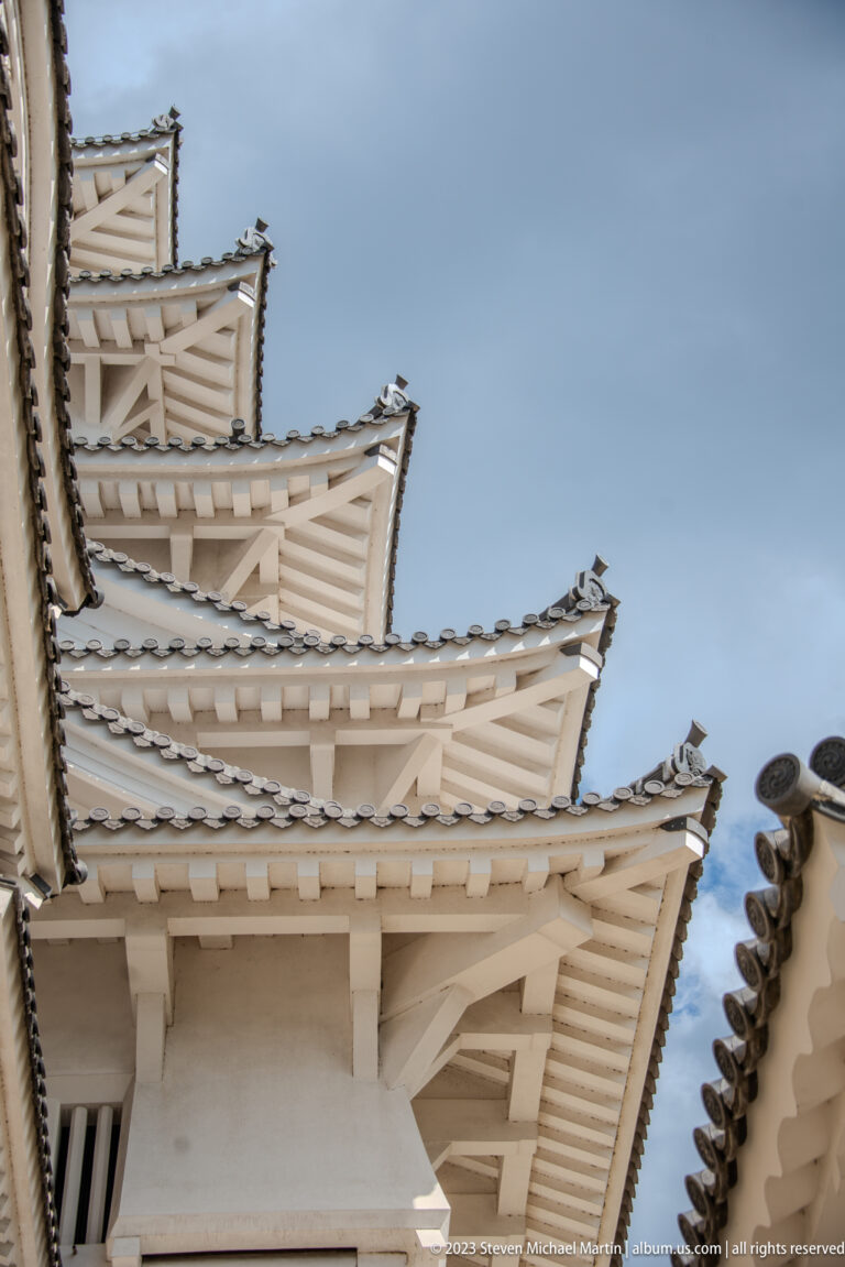 Low-angle view of layered castle roofs against the sky.