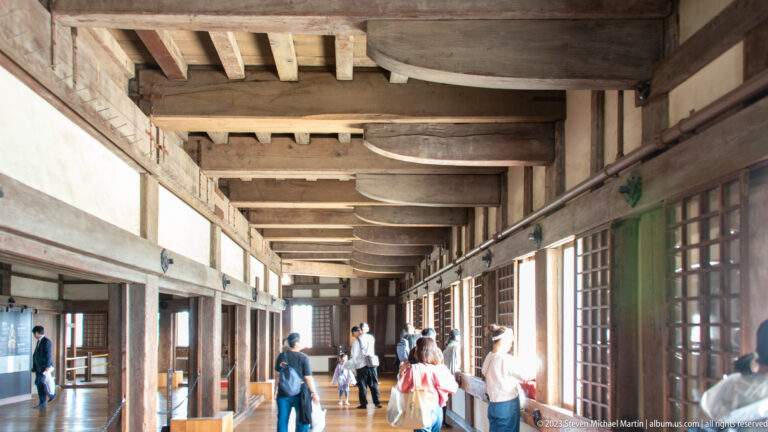 Long wooden interior corridor with visitors inside Himeji Castle.