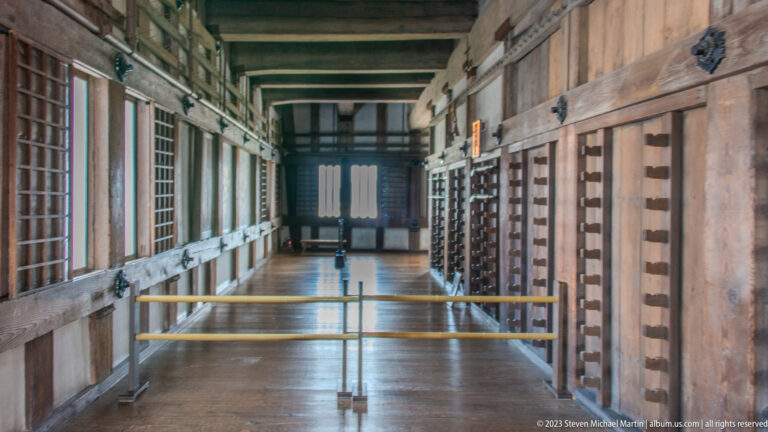 Long wooden corridor inside Himeji Castle with visitor barriers.