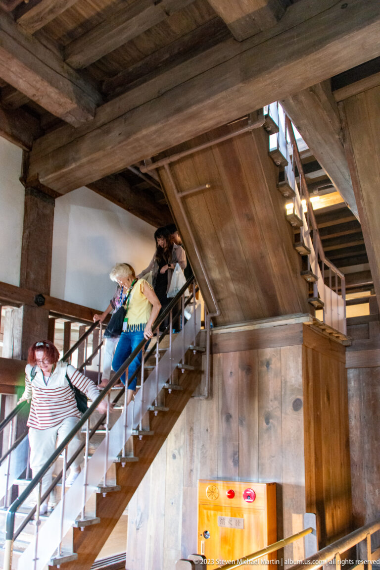 Visitors on a wooden staircase inside Himeji Castle.