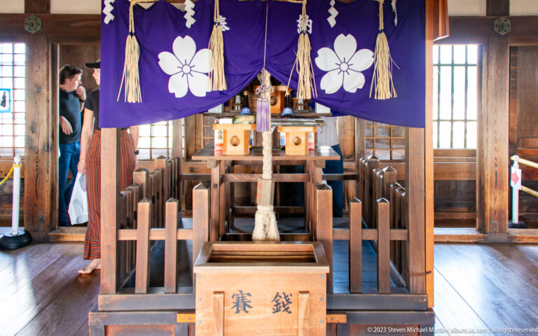 Small shrine with purple crest curtains and a wooden offertory box inside Himeji Castle.