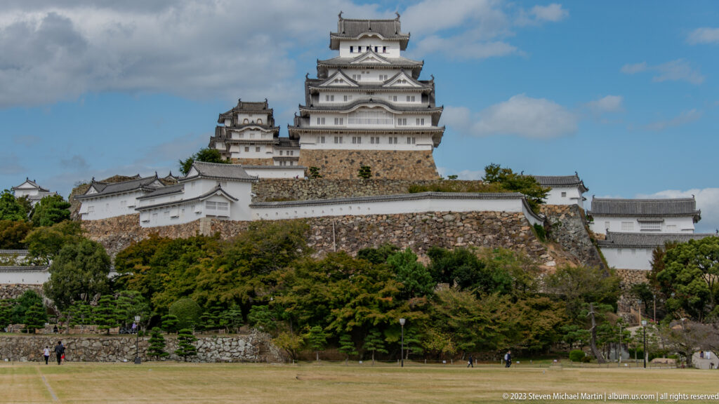 Himeji Castle’s white multi-tiered keep complex rising above sloped stone walls and trees.