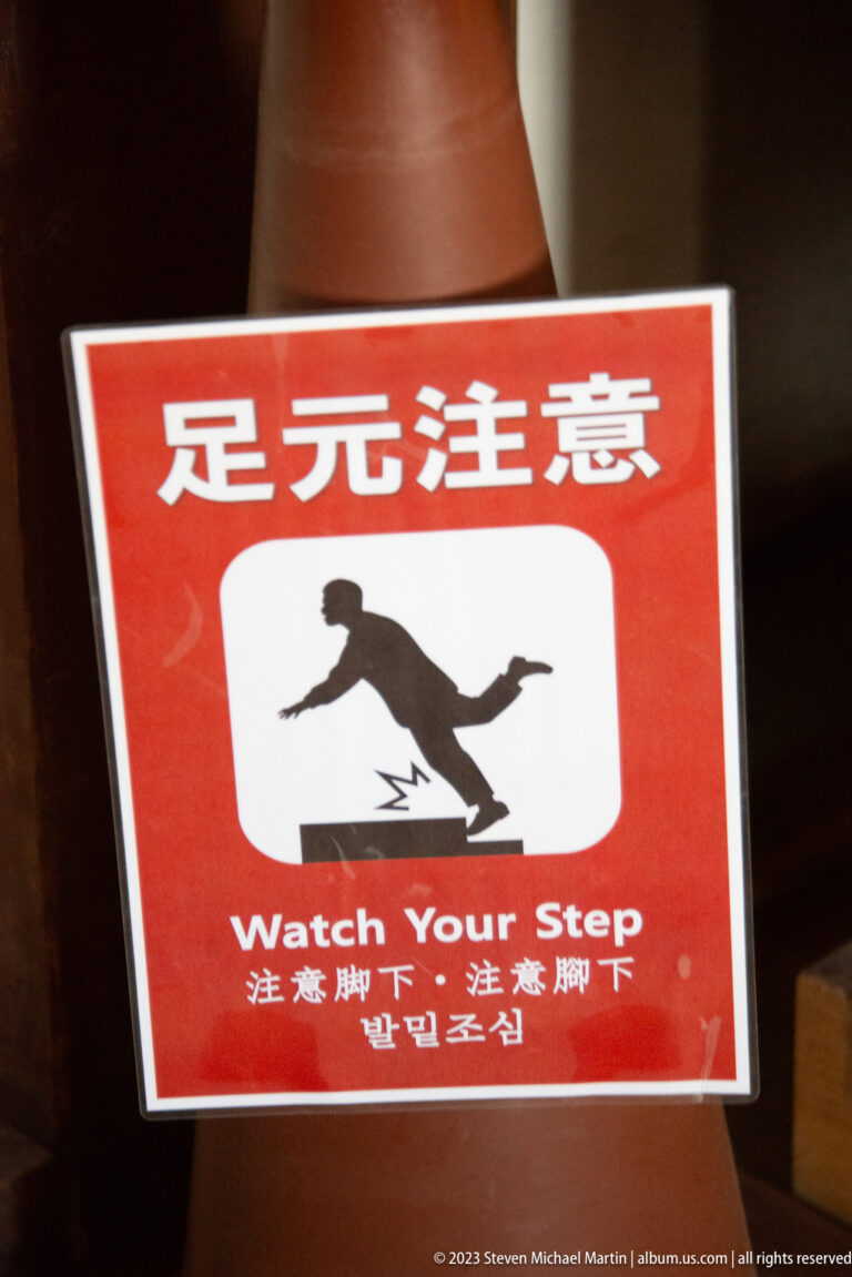 Red multilingual 'Watch Your Step' safety sign.