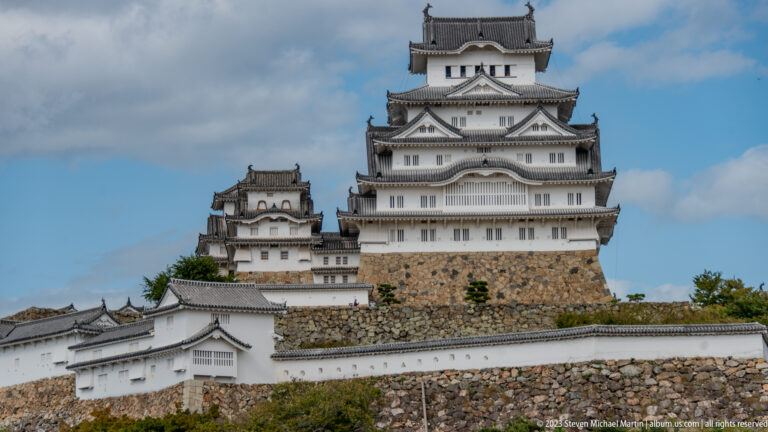 Close exterior view of Himeji Castle’s white keep above adjoining walls and broad sloping stone ramparts.