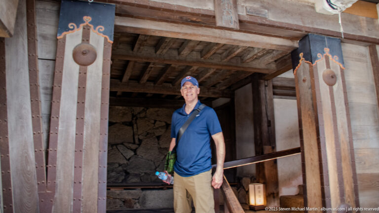 Visitor beside a large timber doorway inside Himeji Castle.